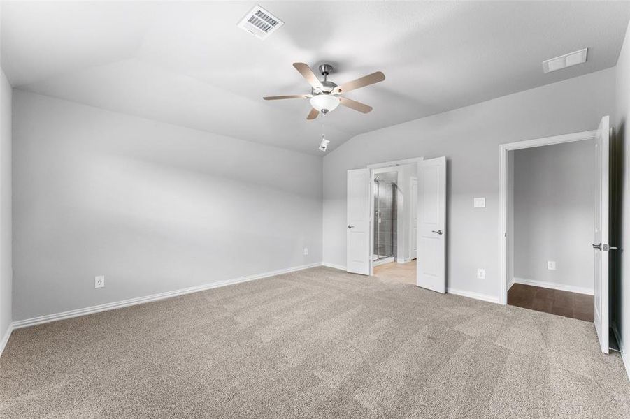 Unfurnished bedroom featuring carpet flooring, vaulted ceiling, connected bathroom, and ceiling fan Unfurnished bedroom featuring carpet flooring, vaulted ceiling, connected bathroom, and ceiling fan