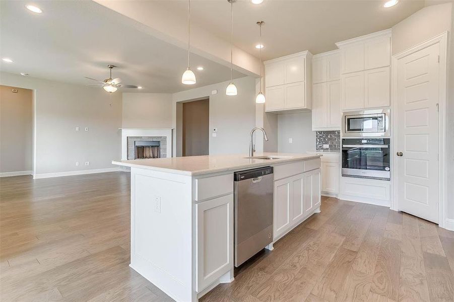 Kitchen featuring ceiling fan, white cabinets, an island with sink, stainless steel appliances, and light wood-type flooring