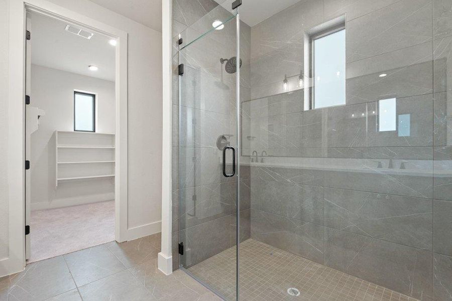 Full bath with a walk in closet, a shower stall, light tile patterned floors, and light colored carpet