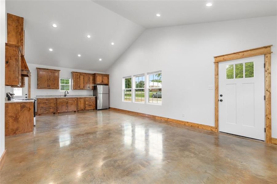 Kitchen with electric range oven, freestanding refrigerator, brown cabinets, concrete flooring, and healthy amount of natural light Kitchen with electric range oven, freestanding refrigerator, brown cabinets, concrete flooring, and healthy amount of natural light
