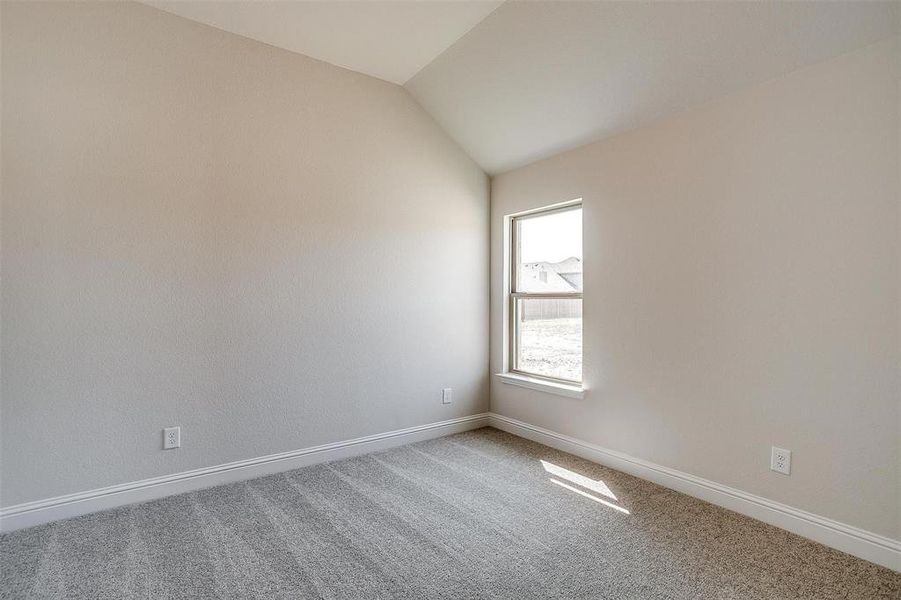 Carpeted spare room with vaulted ceiling