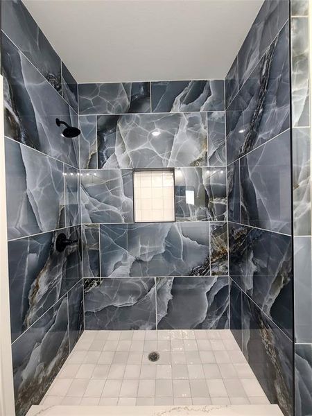 Bathroom featuring a tile shower and tile walls