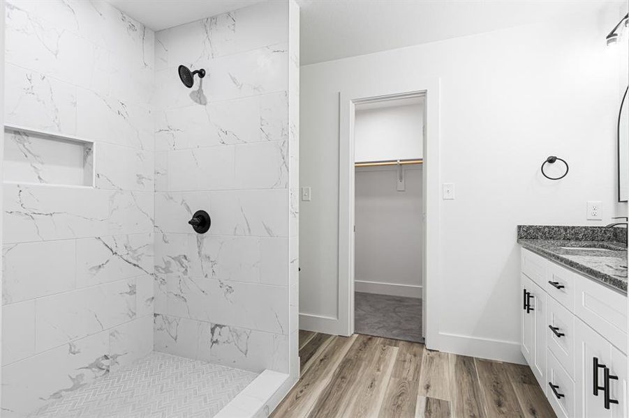 Bathroom featuring vanity, a shower stall, a walk in closet, and light wood-style flooring