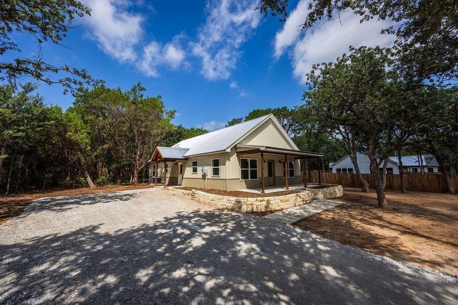 View of front of house featuring gravel driveway and a metal roof