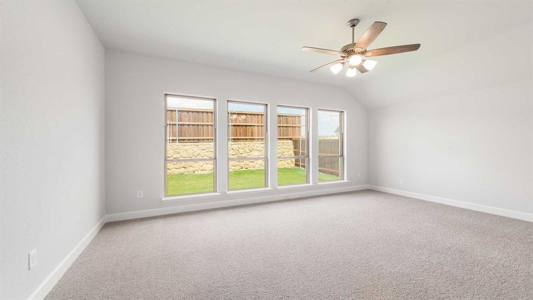 Empty room featuring lofted ceiling, ceiling fan, and carpet floors