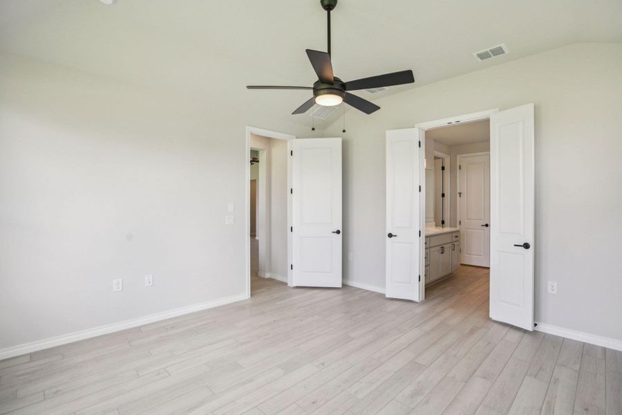 Unfurnished bedroom featuring light wood-type flooring, ceiling fan, and ensuite bath