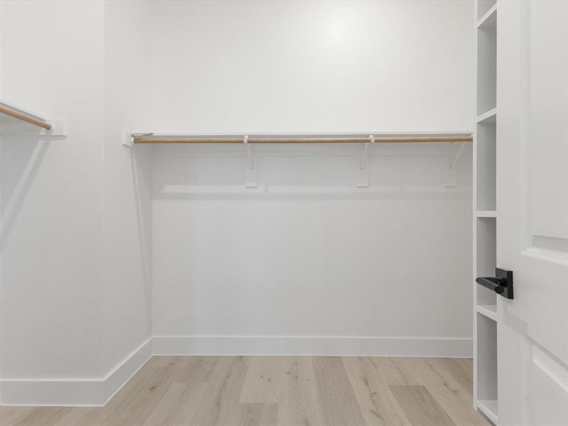Primary closet with light wood-type flooring Primary closet with light wood-type flooring
