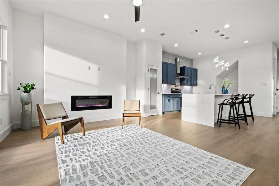 Living room with light wood-style floors, recessed lighting, and a glass covered fireplace