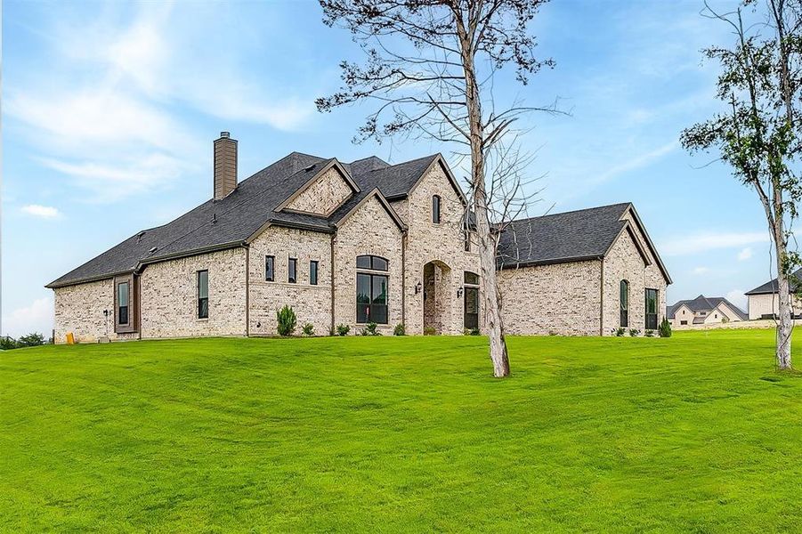 French country inspired facade with a front lawn