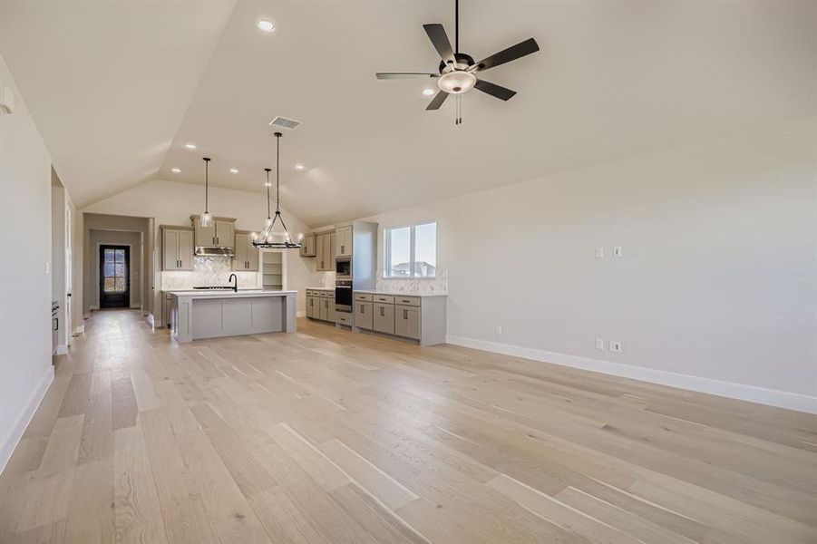 Unfurnished living room with vaulted ceiling, recessed lighting, light wood-style floors, and a ceiling fan