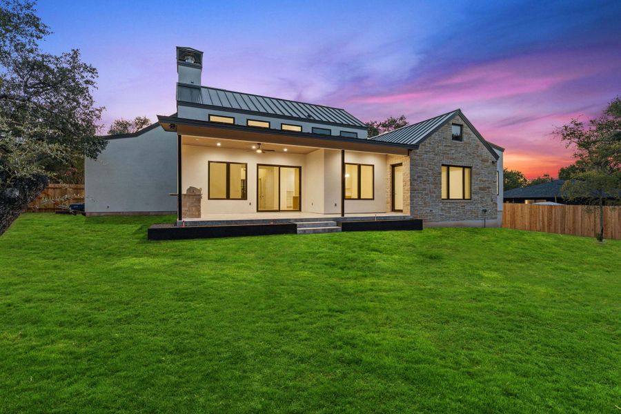 A spacious green lawn sits behind this modern residence showcasing mixed stone and stucco siding.