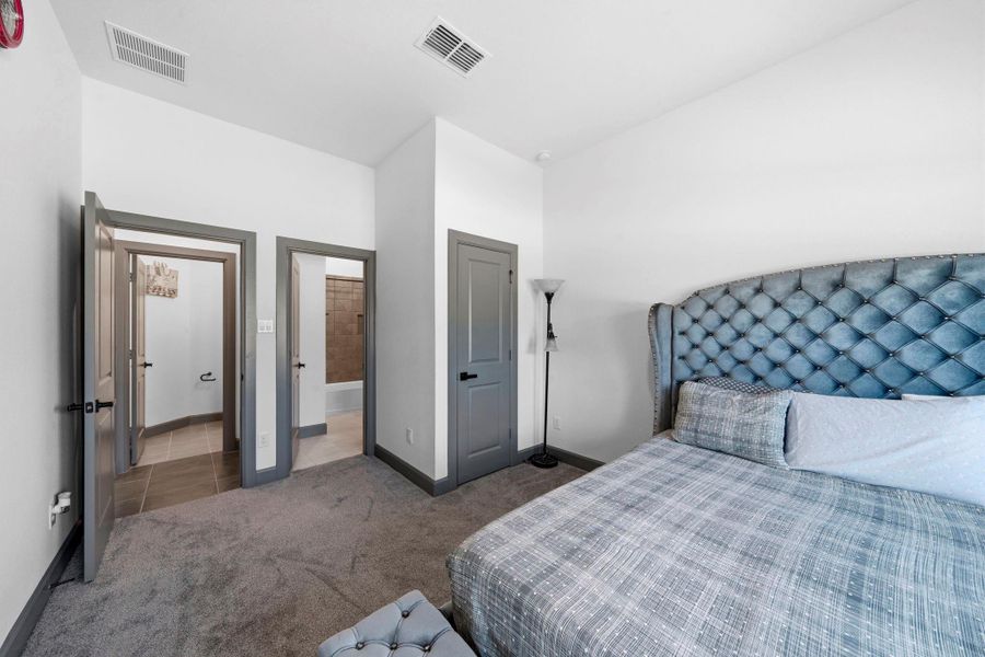Spacious secondary bedroom featuring plush carpeting, elevated ceiling height, and easy access to nearby bath—ideal for guests or family.