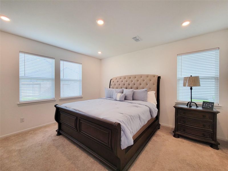 This spacious Primary bedroom features a large room. Ample natural light streams in through three windows.