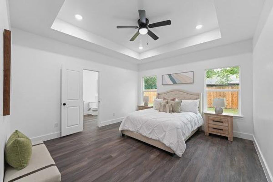 Spacious bedroom with tray ceiling, recessed lighting, and a ceiling fan Spacious bedroom with tray ceiling, recessed lighting, and a ceiling fan