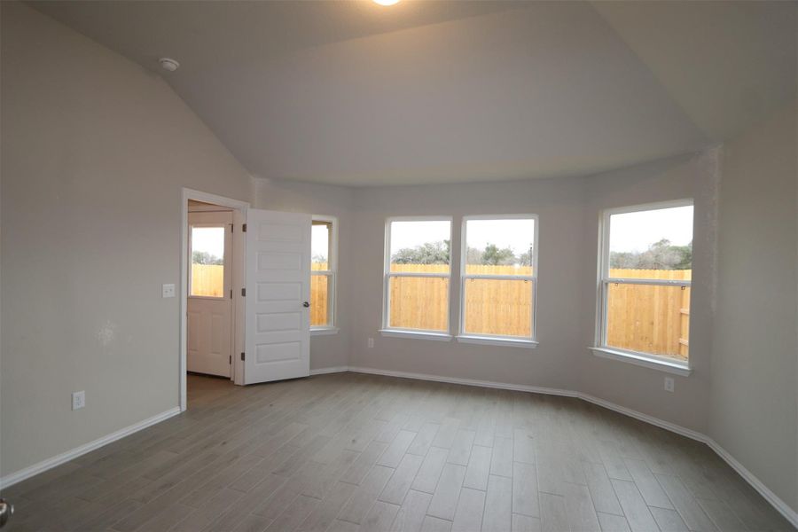 Empty room featuring light hardwood / wood-style flooring and vaulted ceiling