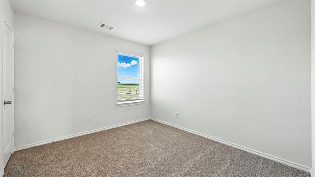 Carpeted interior room featuring a single window with blinds, recessed ceiling lighting, and a white paneled door with a dark handle