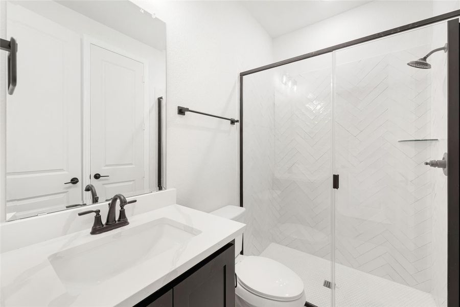 Bathroom with white quartz vanity, glass walk-in shower with herringbone tile, and dark bronze fixtures Bathroom with white quartz vanity, glass walk-in shower with herringbone tile, and dark bronze fixtures