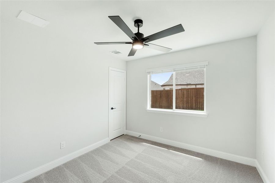 Empty bedroom with gray carpet, white walls, ceiling fan, and single window