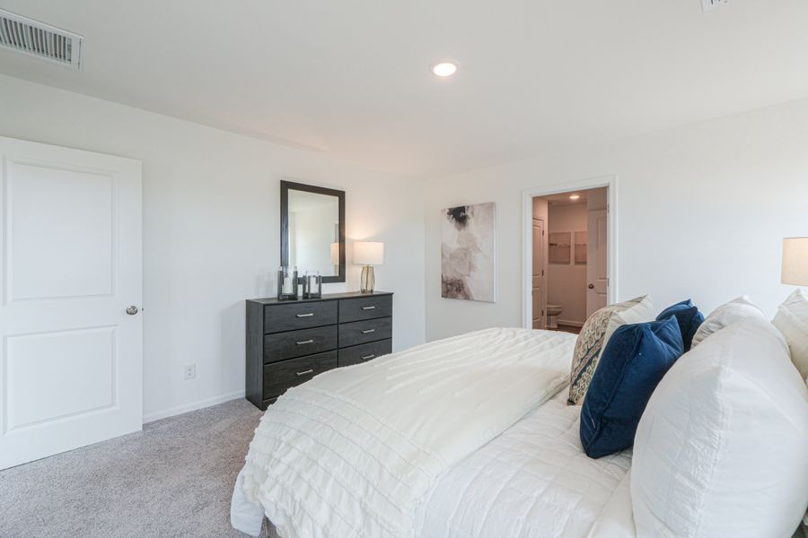 A bedroom with a bed and dresser.