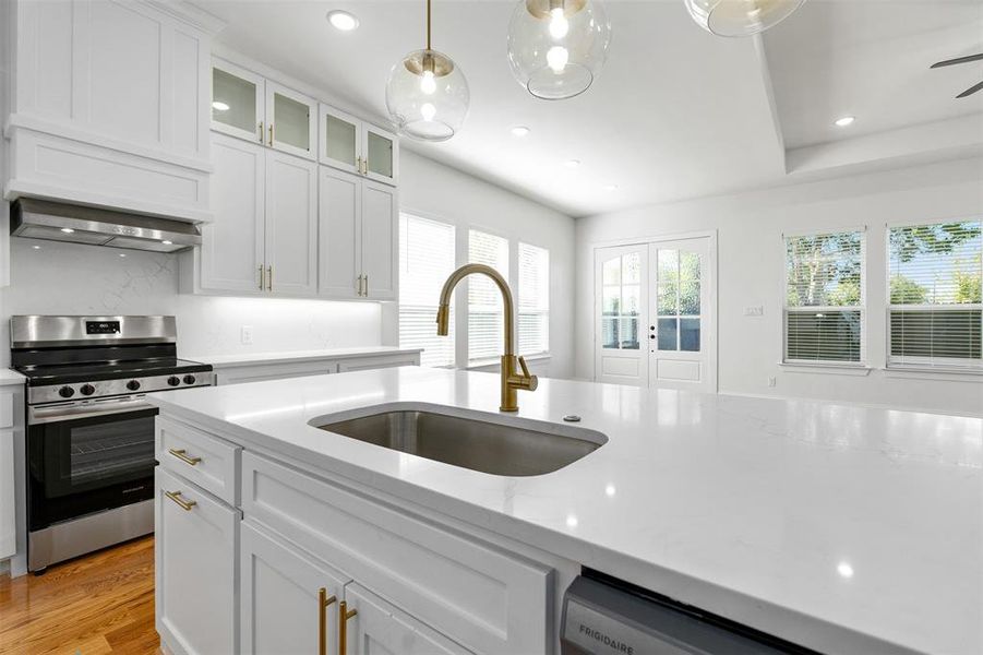 Kitchen featuring white cabinetry, sink, appliances with stainless steel finishes, light wood-type flooring, and pendant lighting