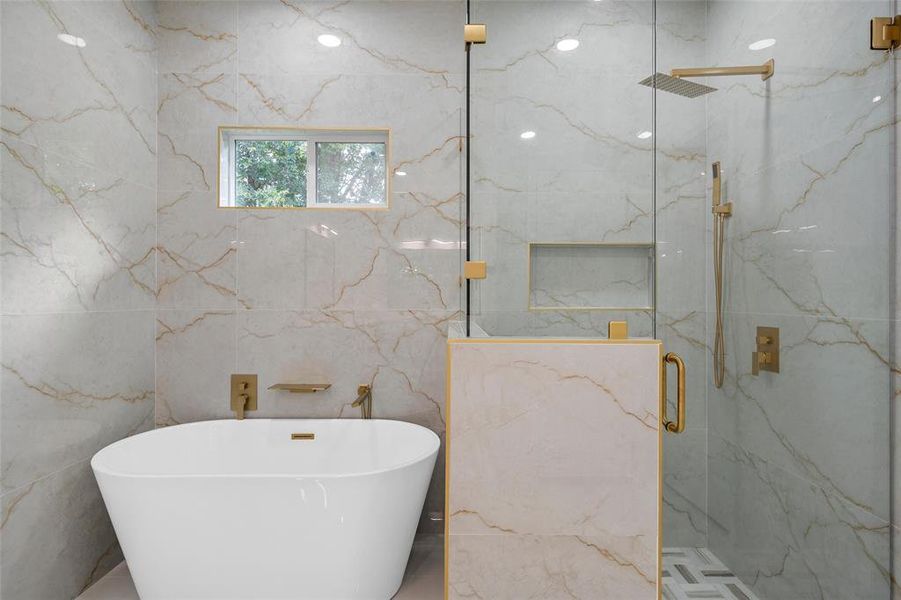 Freestanding soaking tub with gold-finish fixtures and an adjacent glass-enclosed shower Freestanding soaking tub with gold-finish fixtures and an adjacent glass-enclosed shower