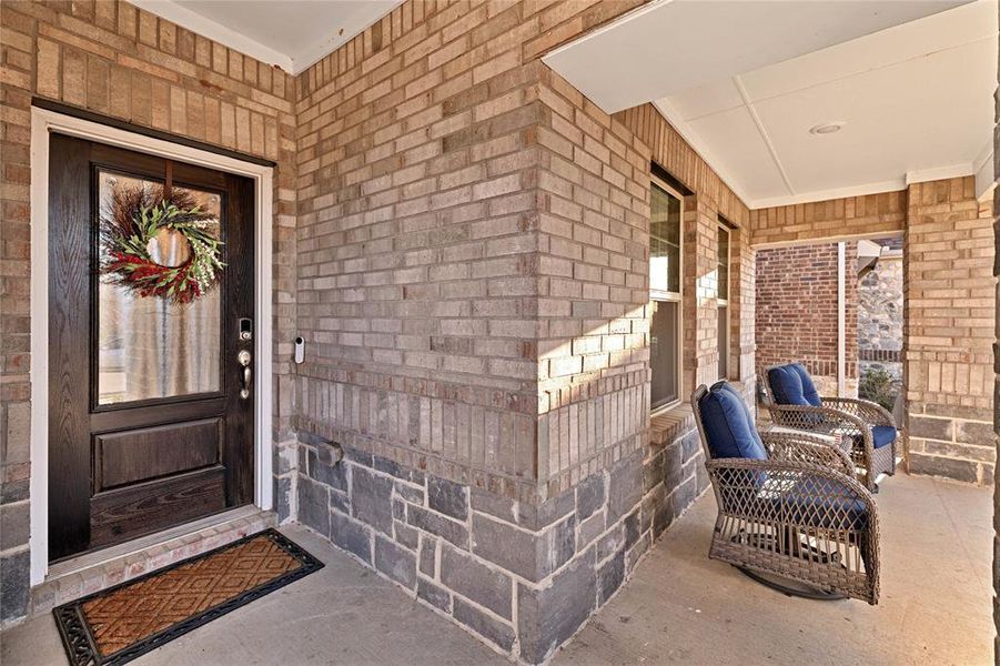 Entrance to property with a porch and brick siding