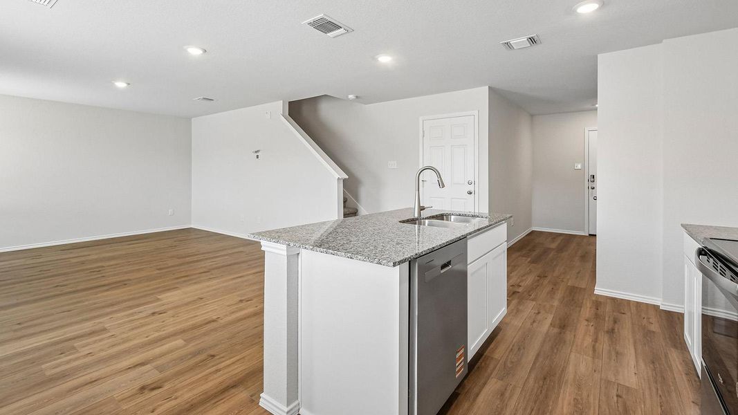 A streamlined kitchen island with a granite countertop and integrated dishwasher anchors this bright, open-concept living space.
