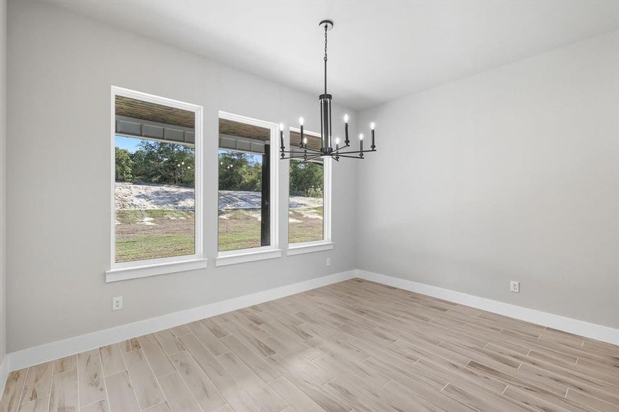 Unfurnished dining area featuring a chandelier and wood finish floors Unfurnished dining area featuring a chandelier and wood finish floors
