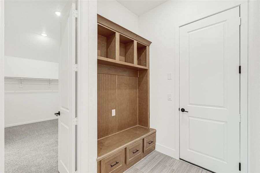 Mudroom with built-in wood locker, bench seat, drawers, and upper cubbies next to a walk-in closet entrance. Mudroom with built-in wood locker, bench seat, drawers, and upper cubbies next to a walk-in closet entrance.