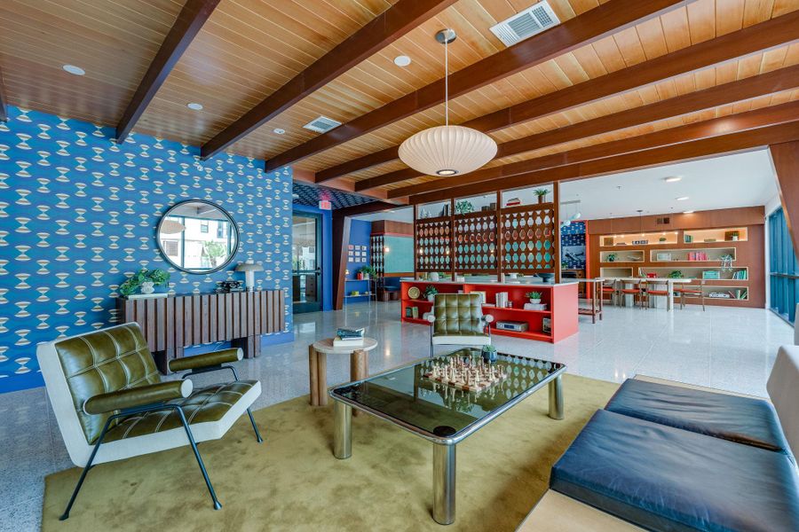 The property features an inviting common area with a distinctive wood-beamed ceiling, stylish patterned wallpaper, and polished flooring