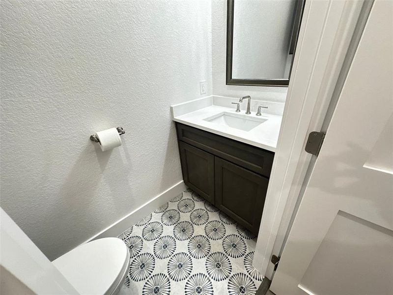 Bathroom with baseboards, a textured wall, tile patterned flooring, and vanity