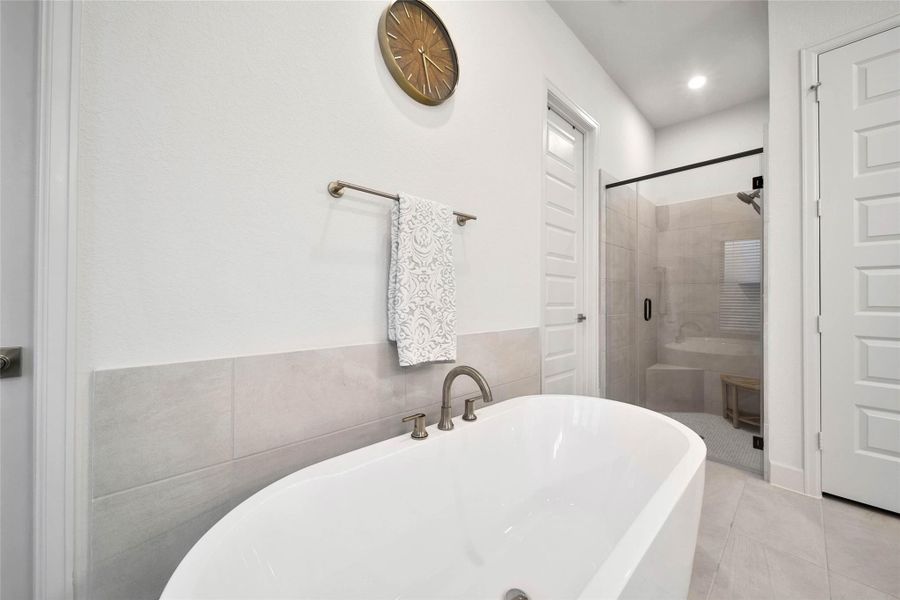 Deep soaking tub provides a relaxing retreat, complemented by abundant natural light and the spacious, beautifully appointed bath.