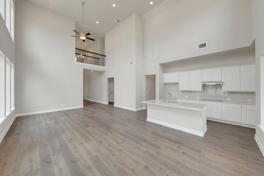 Unfurnished living room featuring a high ceiling, light wood finished floors, a ceiling fan, and recessed lighting Unfurnished living room featuring a high ceiling, light wood finished floors, a ceiling fan, and recessed lighting