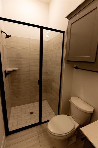 Bathroom featuring vanity, toilet, and a shower with shower door