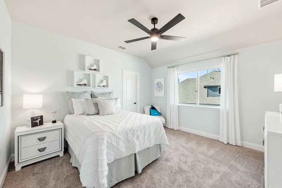 Bedroom with white walls, ceiling fan, carpet flooring, and wall-mounted display shelves above the bed Bedroom with white walls, ceiling fan, carpet flooring, and wall-mounted display shelves above the bed
