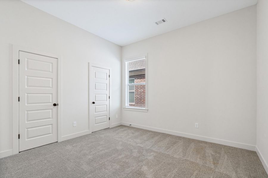 Unfurnished bedroom with light carpet and baseboards