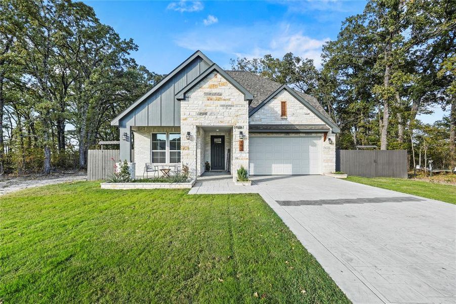 View of front of property featuring decorative driveway, stone siding, board and batten siding, and a garage