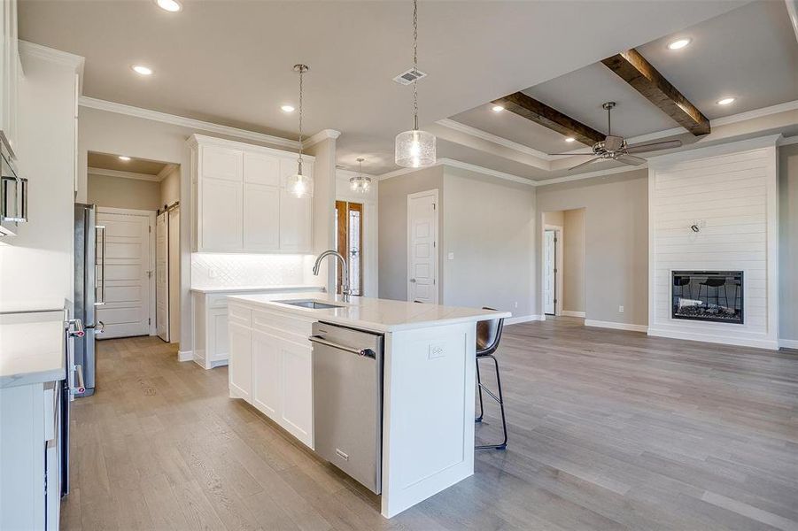 Kitchen featuring white cabinetry, appliances with stainless steel finishes, and a kitchen island with sink