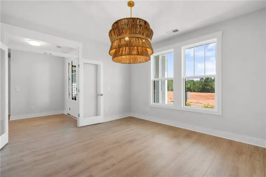 A spacious room features a unique chandelier, tall A spacious room features a unique chandelier, tall