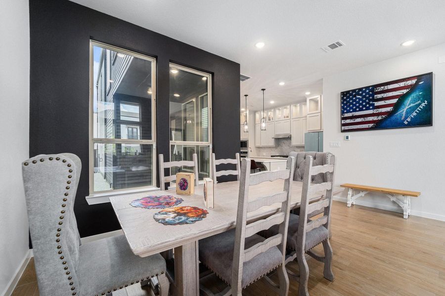 Dining area connects seamlessly to the chef’s kitchen with quartz counters and pendant lighting.