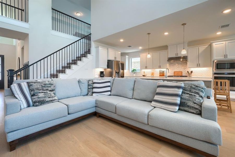 Living room with a high ceiling and light wood-type flooring