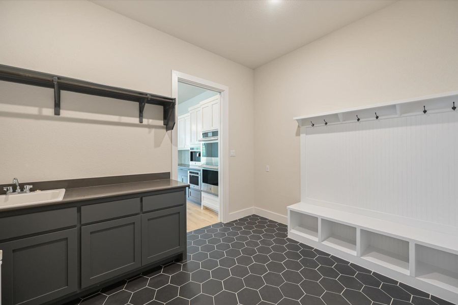 A versatile utility area with a sink and storage, featuring a mudroom-style bench with hooks.