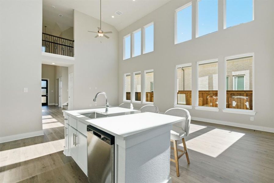 Kitchen with white cabinets, dishwasher, open floor plan, a center island with sink, and dark wood-style flooring
