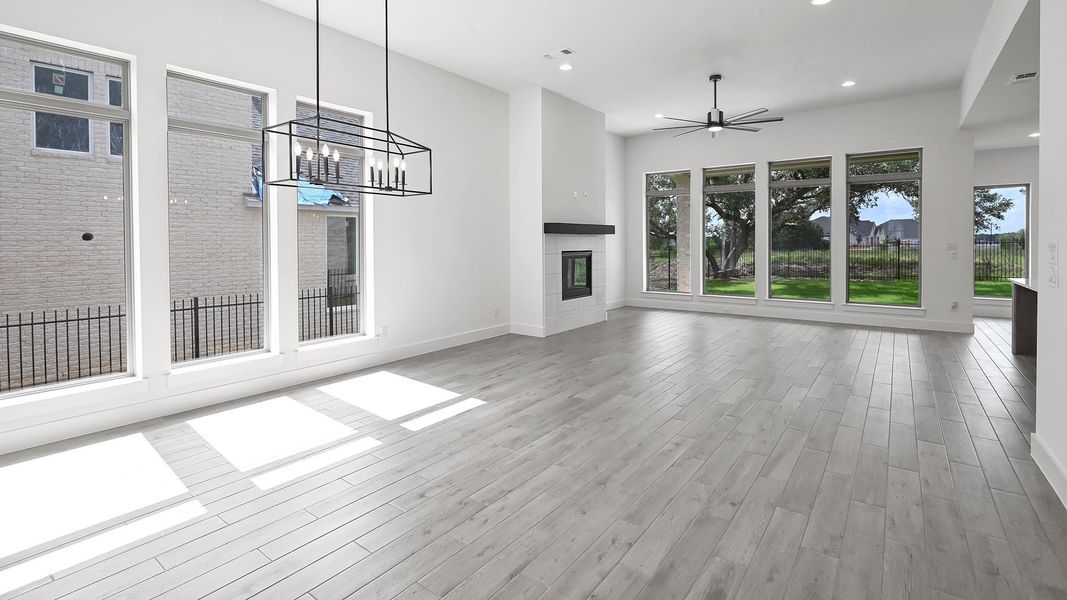 Unfurnished living room featuring healthy amount of natural light, a ceiling fan, recessed lighting, wood finished floors, and a tiled fireplace Unfurnished living room featuring healthy amount of natural light, a ceiling fan, recessed lighting, wood finished floors, and a tiled fireplace
