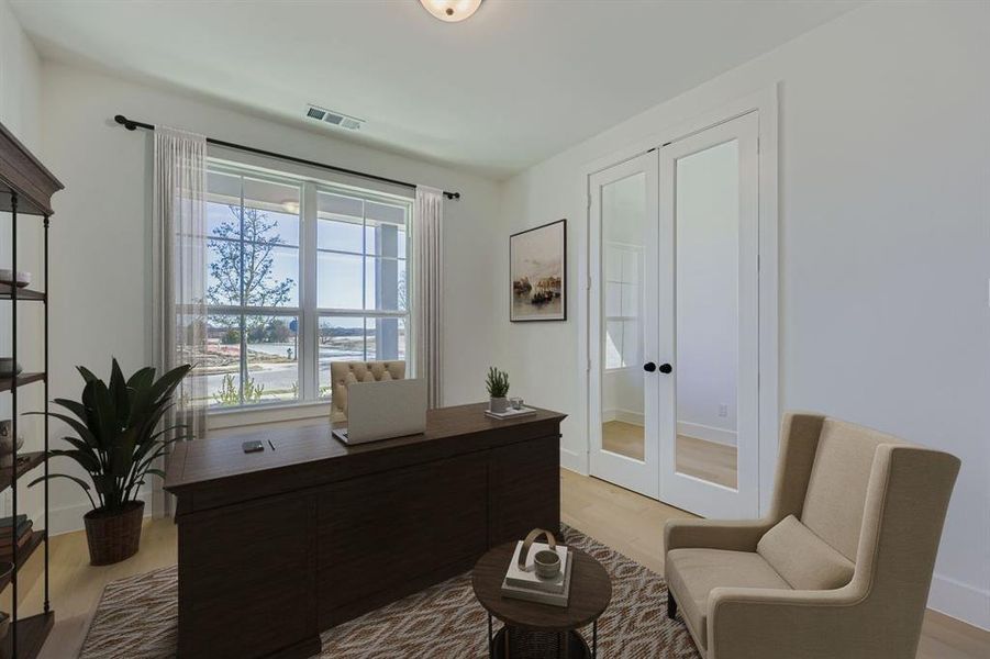 Virtually staged photo - Office area with french doors and light wood-style floors