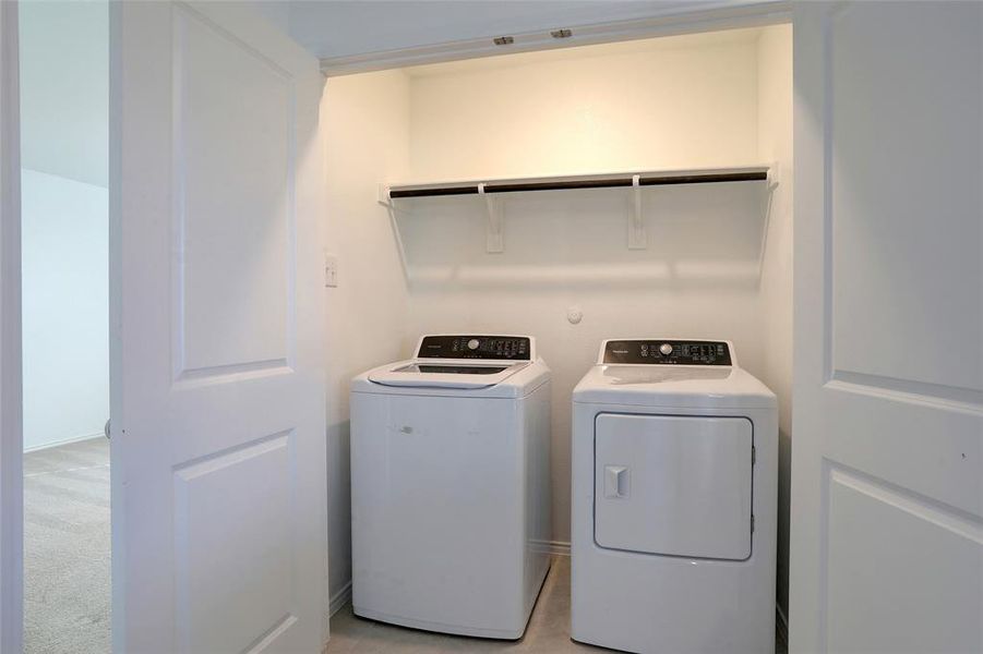 Laundry area featuring washer and clothes dryer and light carpet