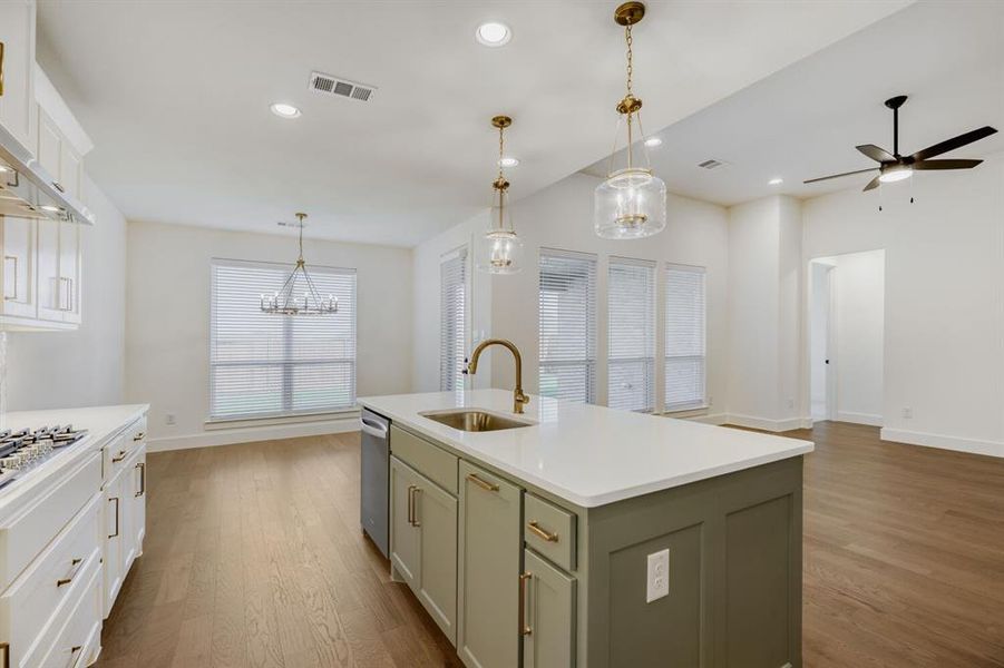 Spacious open-concept living area featuring a kitchen island with sink, white countertops, and wood-finish flooring