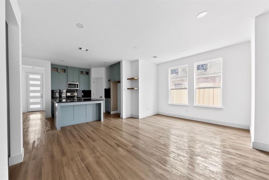 Kitchen with open floor plan, a center island, glass fronted cabinets, dark countertops, and light wood-style floors