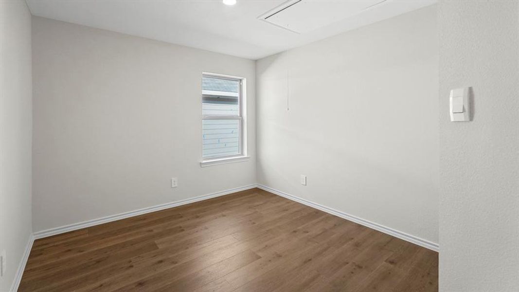 Spare room featuring attic access and dark wood-type flooring
