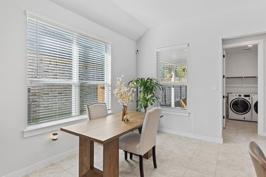 Dining room with lofted ceiling, separate washer and dryer, and light tile patterned floors